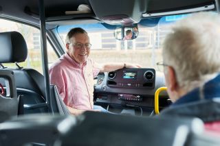 Vrijwilliger als chauffeur in de ZINN bus met een cliënt van de Buurthuiskamer
